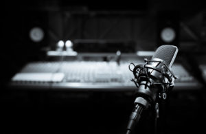 Black and white photo of a microphone in a recording studio